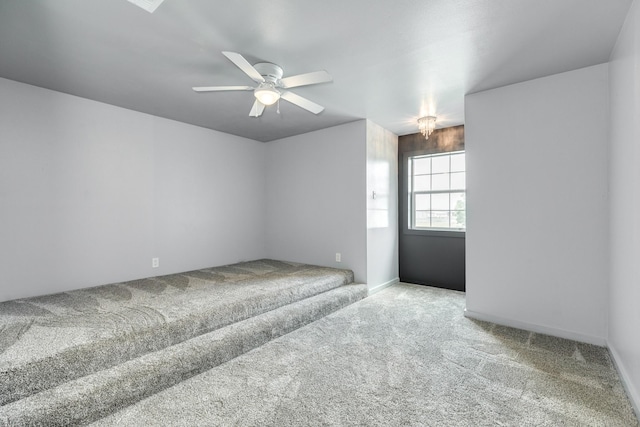 carpeted empty room featuring stairway, baseboards, and ceiling fan