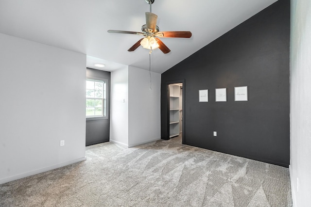 spare room featuring vaulted ceiling, ceiling fan, carpet flooring, and baseboards