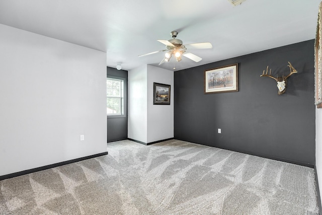 spare room with a ceiling fan, baseboards, and carpet