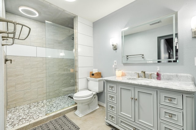 bathroom with toilet, vanity, visible vents, tile patterned floors, and a tile shower