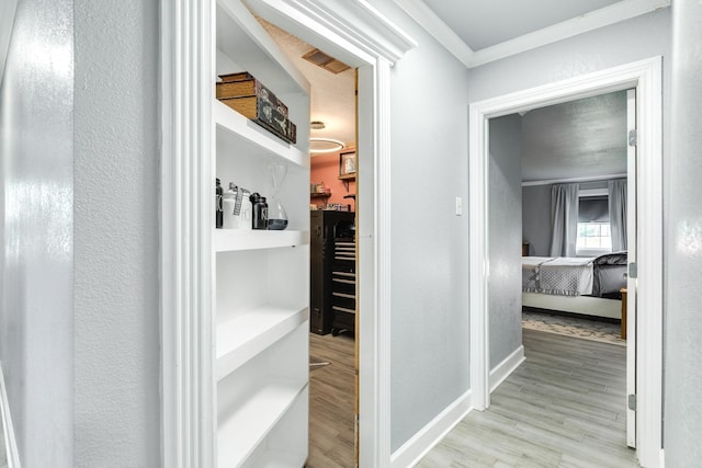 corridor with baseboards, visible vents, crown molding, and wood finished floors