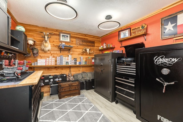 kitchen with butcher block countertops, light wood finished floors, wood walls, and a textured ceiling