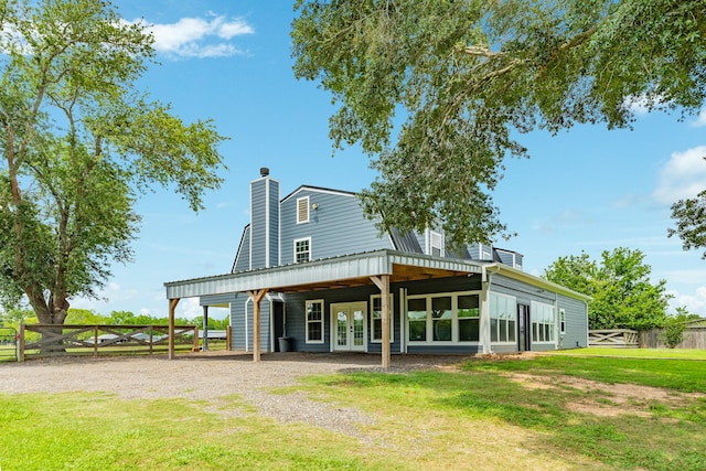 rear view of property with a chimney, french doors, fence, and a lawn