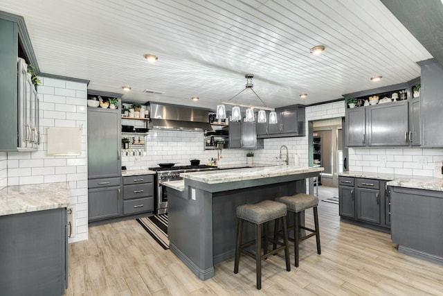 kitchen featuring open shelves, wall chimney exhaust hood, high end stainless steel range oven, light stone countertops, and backsplash