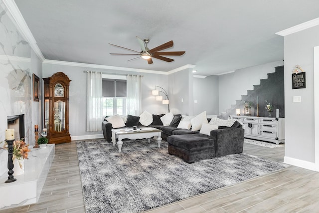 living area featuring baseboards, stairway, light wood finished floors, and ceiling fan