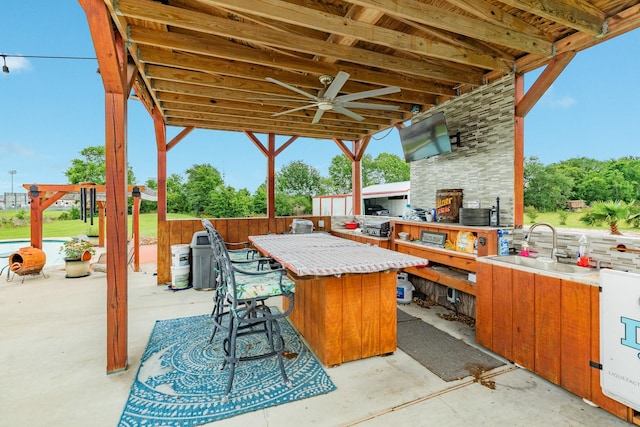view of patio / terrace with a ceiling fan, an outdoor kitchen, outdoor wet bar, and a sink