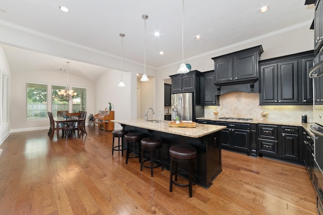 17803 Netherby Ln, Richmond, TX 77407 - kitchen featuring appliances with stainless steel finishes, dark cabinets, light stone counters, light wood-style floors, and recessed lighting