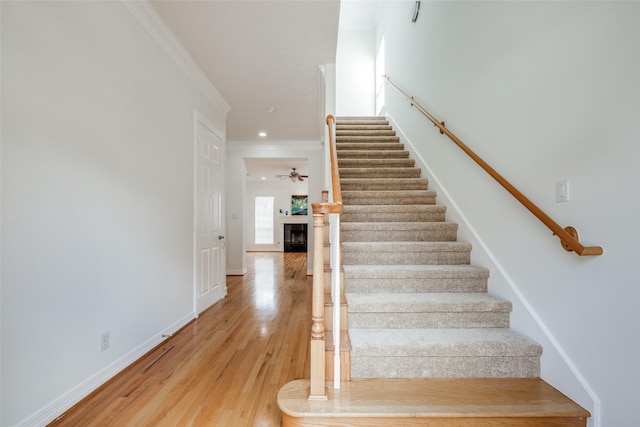 2827 Briarhurst Park, Houston, TX 77057 - stairway featuring a fireplace, ornamental molding, baseboards, and wood finished floors