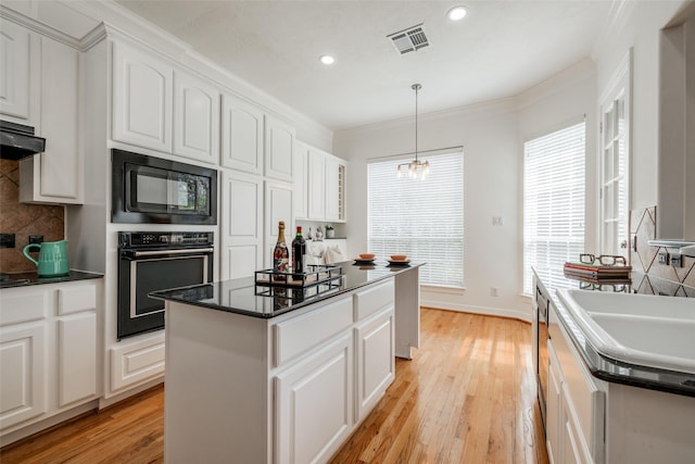 2827 Briarhurst Park, Houston, TX 77057 - kitchen featuring ornamental molding, visible vents, a kitchen island, backsplash, and black appliances