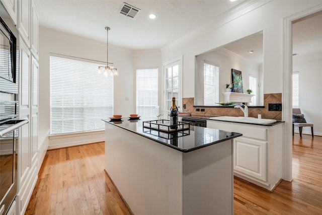 2827 Briarhurst Park, Houston, TX 77057 - kitchen with a sink, light wood-type flooring, visible vents, a center island, and white cabinets