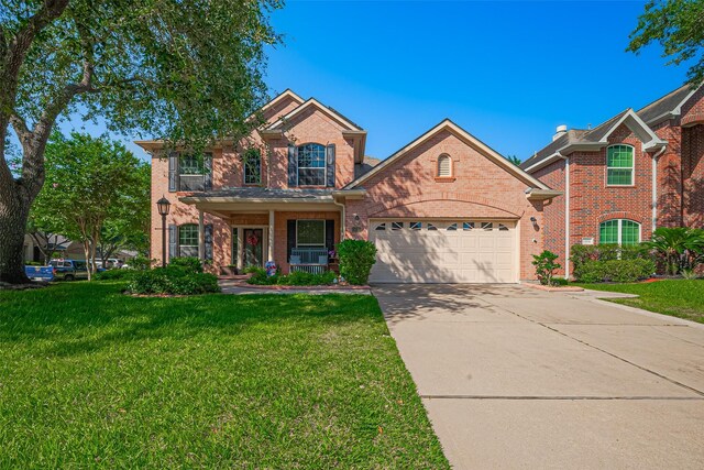traditional home featuring brick siding, an attached garage, a front yard, concrete driveway, and a porch
