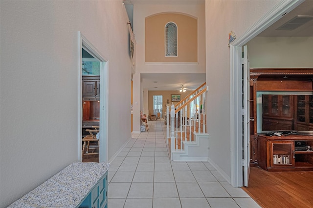 entryway with light tile patterned floors, stairway, a high ceiling, ceiling fan, and baseboards
