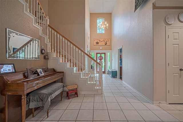 entryway featuring healthy amount of natural light, light tile patterned floors, baseboards, a towering ceiling, and stairs