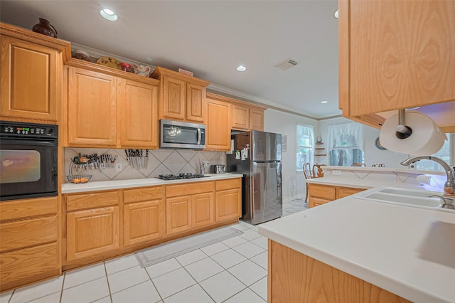 kitchen with stainless steel appliances, a sink, light countertops, decorative backsplash, and light tile patterned floors
