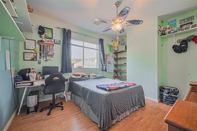 bedroom featuring light wood-style floors, baseboards, an office area, and a ceiling fan