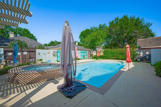 view of swimming pool with an in-ground hot tub, fence, and a patio