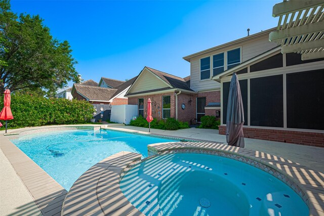 view of swimming pool featuring a sunroom, a pool with connected hot tub, a patio, and fence