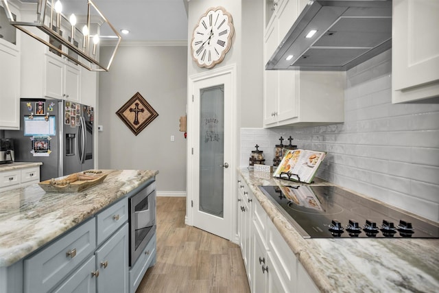 kitchen with under cabinet range hood, crown molding, white cabinetry, decorative backsplash, and appliances with stainless steel finishes