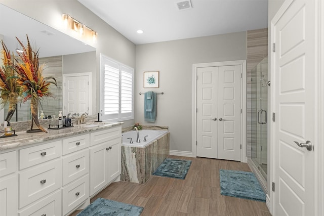 bathroom featuring vanity, a garden tub, a shower stall, and visible vents