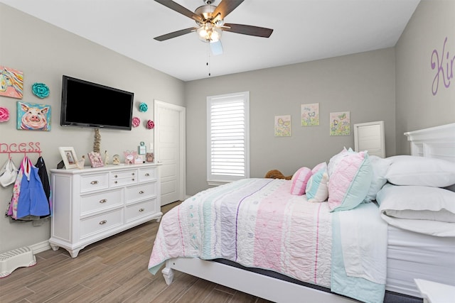 bedroom with a ceiling fan, wood finished floors, and baseboards