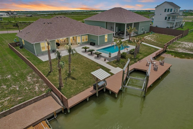 back of property at dusk featuring a patio area, boat lift, a fenced backyard, a fenced in pool, and a water view