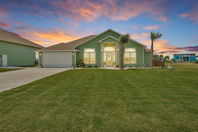 view of front facade with a front lawn, roof with shingles, driveway, and a garage