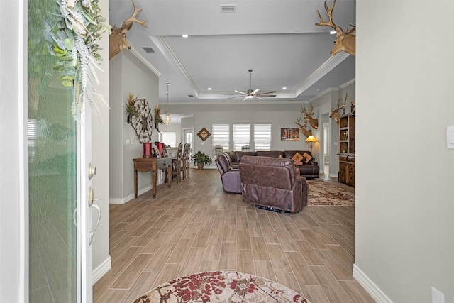 living room with a tray ceiling, a ceiling fan, visible vents, and light wood-style floors