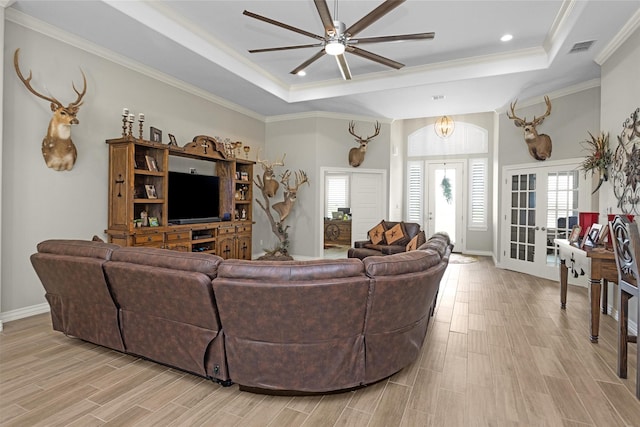 living area featuring a ceiling fan, visible vents, a raised ceiling, and ornamental molding
