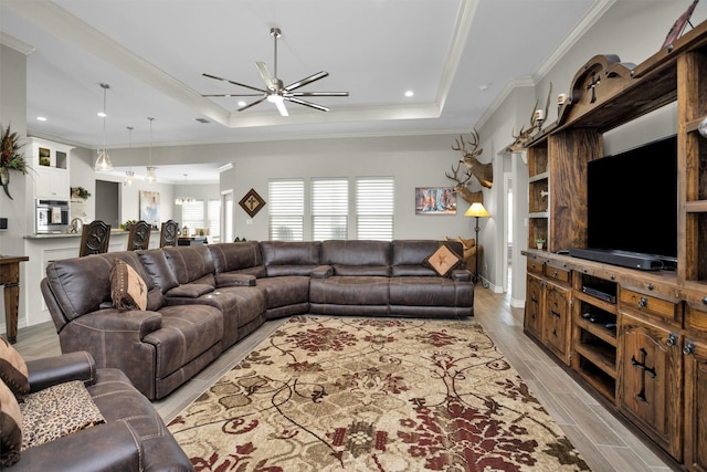 living room with ceiling fan, a raised ceiling, crown molding, and light wood finished floors