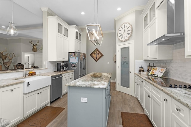 kitchen with a sink, stainless steel appliances, recessed lighting, wall chimney exhaust hood, and decorative backsplash