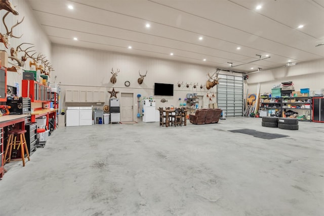 garage featuring freestanding refrigerator, a workshop area, recessed lighting, and washer and dryer