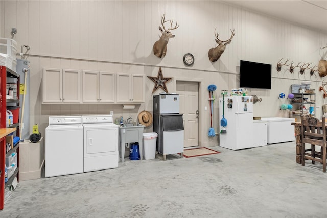 garage with washing machine and clothes dryer, freestanding refrigerator, and refrigerator