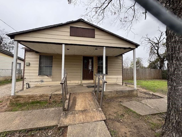bungalow-style home featuring covered porch and fence