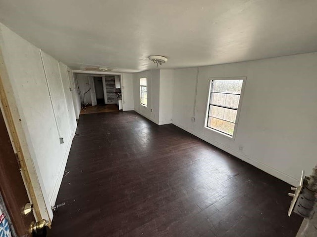unfurnished living room featuring dark wood-style flooring and baseboards