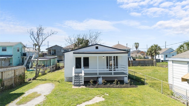 rear view of property featuring a porch, a residential view, a lawn, and a fenced backyard