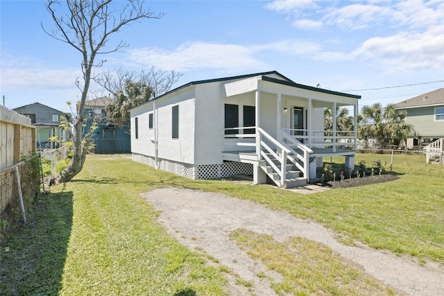 view of front of property featuring a fenced backyard, stucco siding, covered porch, and a front yard