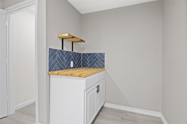 bar with light wood-style floors, tasteful backsplash, and baseboards