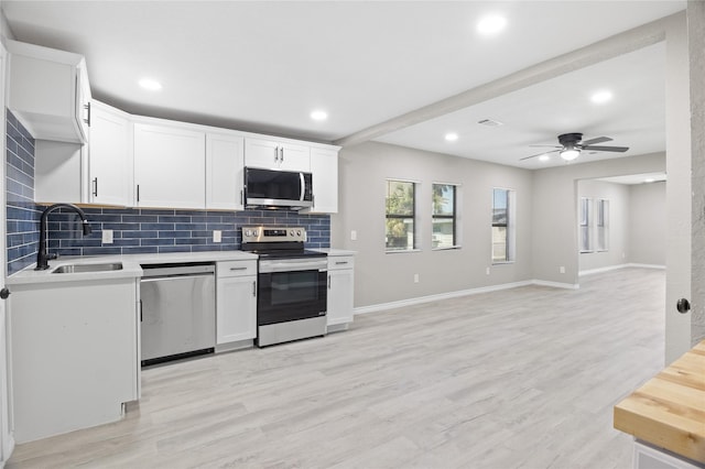 kitchen featuring a sink, tasteful backsplash, light countertops, a ceiling fan, and appliances with stainless steel finishes