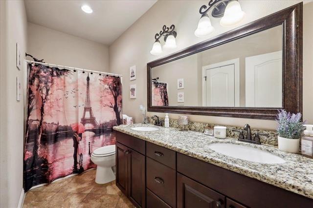 bathroom featuring a sink, double vanity, toilet, and tile patterned floors