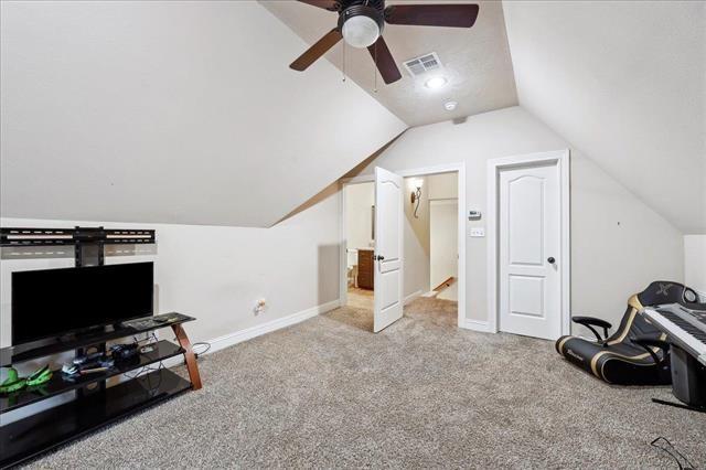 additional living space featuring carpet floors, visible vents, baseboards, ceiling fan, and lofted ceiling