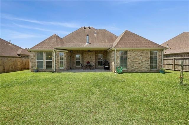 rear view of house featuring a fenced backyard, a patio area, brick siding, and a lawn