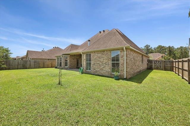 back of property featuring a yard, brick siding, and a fenced backyard