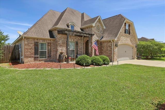 french country home with concrete driveway, brick siding, a garage, and fence