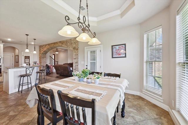 dining room featuring recessed lighting, tile patterned floors, arched walkways, a tray ceiling, and baseboards