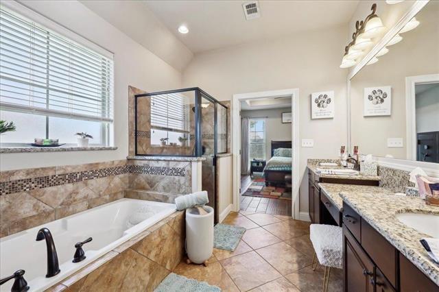 ensuite bathroom featuring connected bathroom, a stall shower, a bath, visible vents, and vanity