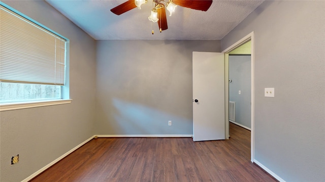 empty room featuring ceiling fan, baseboards, visible vents, and wood finished floors