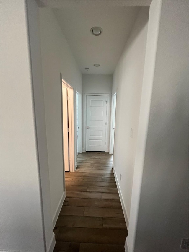 corridor with dark wood-type flooring and baseboards