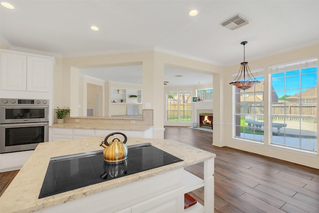 14906 Stonemeade Pl, Cypress, TX 77429 - kitchen with light stone counters, black electric stovetop, double oven, white cabinets, and dark wood-style floors