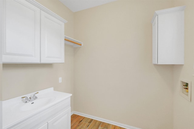 14906 Stonemeade Pl, Cypress, TX 77429 - laundry area featuring baseboards, washer hookup, a sink, light wood-style floors, and cabinet space