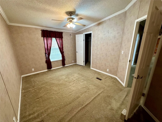 unfurnished bedroom featuring a textured ceiling, ornamental molding, ceiling fan, visible vents, and carpet floors